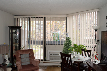 Vertical blinds installed on a patio door, over an air conditioner and a side window.