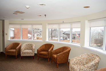 A set of three half-bay windows in a common area of a retirement home. An individual blind covers each window in each half bay.